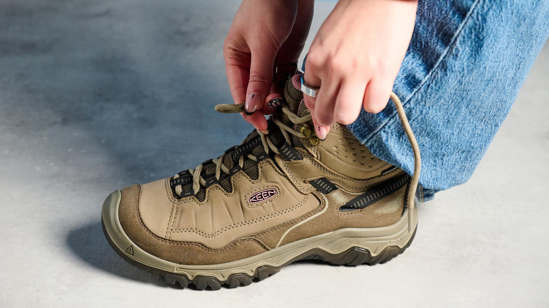 Keen Targhee IV hiking boots photographed in front of a blue background. 